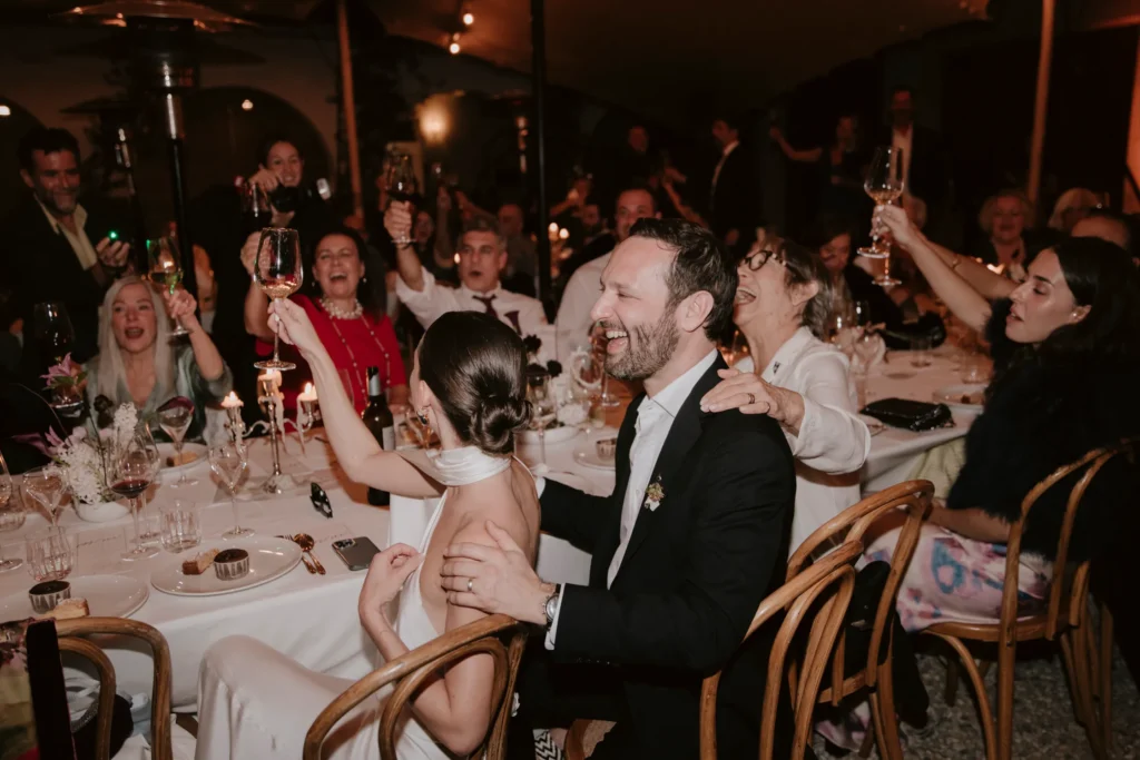 A newly engaged couple celebrating with family and friends during the holidays, raising glasses and enjoying a festive dinner while planning their wedding season.