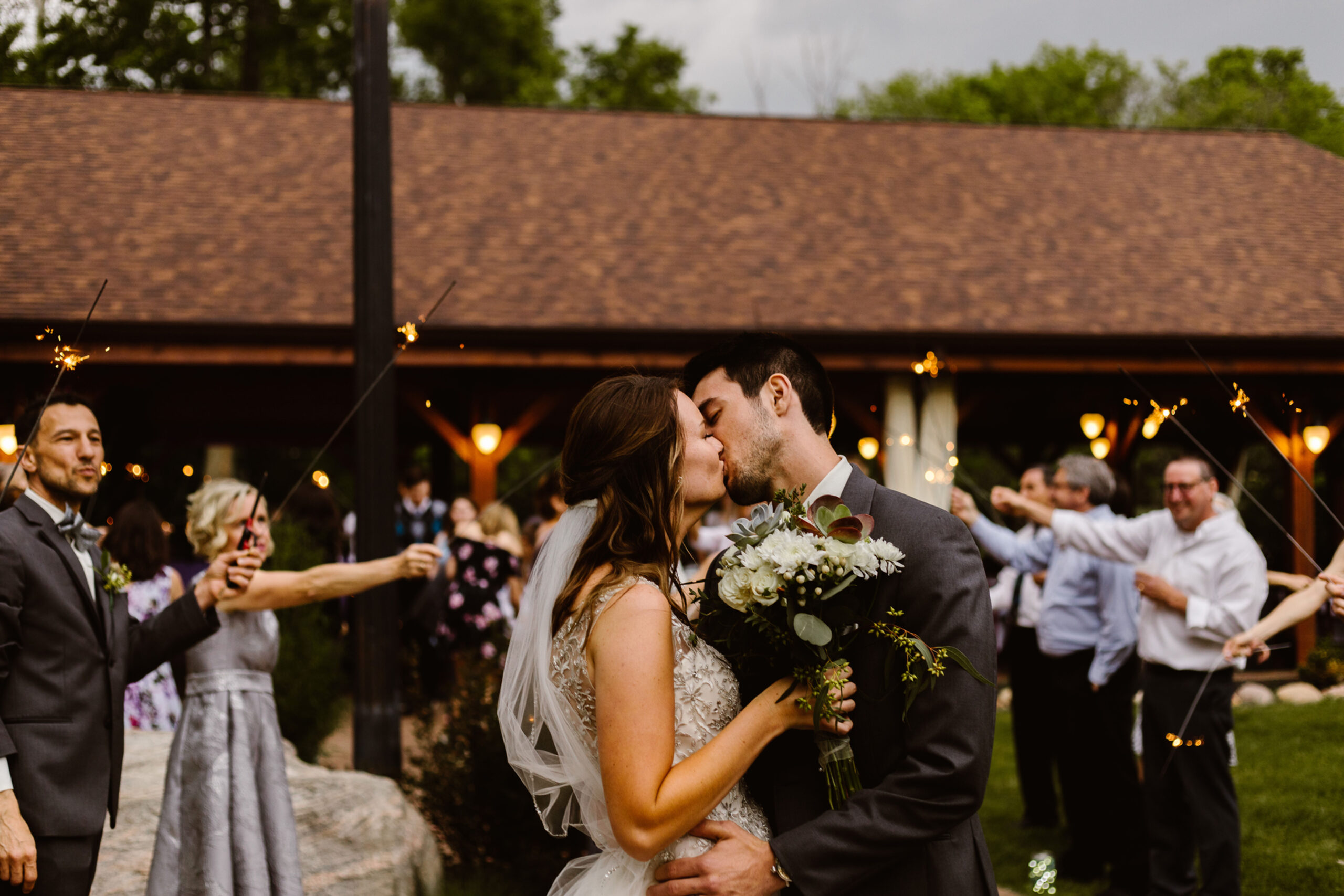 Newlywed couple kissing during a sparkler send-off at an outdoor Southwest Michigan wedding reception