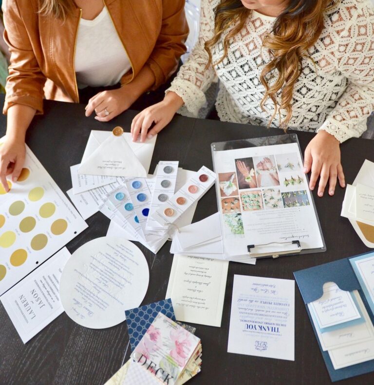 Wedding planner and bride reviewing invitation suite, color samples, and design details during planning meeting